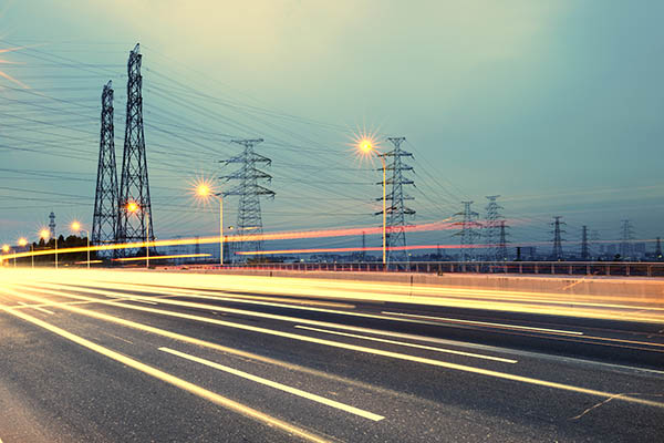 high voltage tower beside traffic on the highway