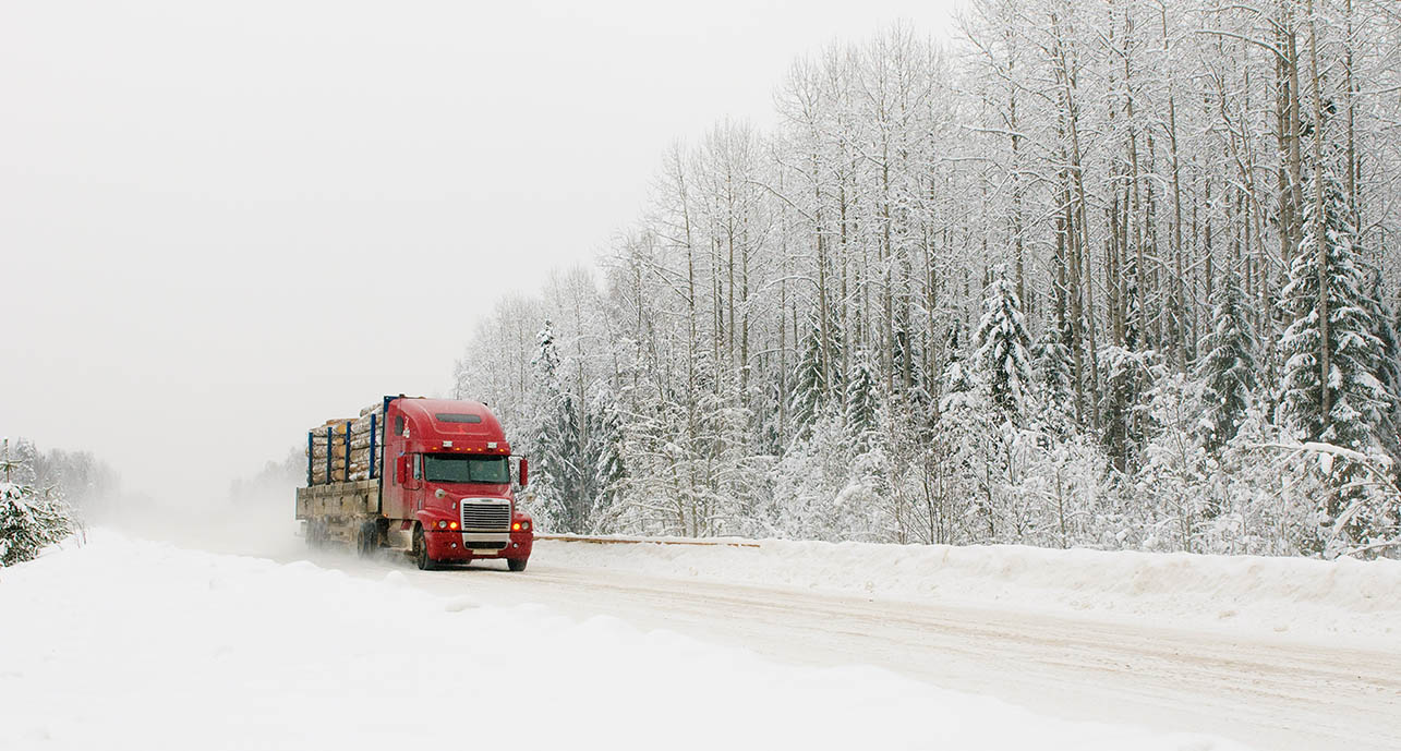 red truck driving on a snowy, winter road