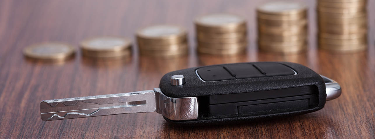a vehicle key and asset with coins in the background