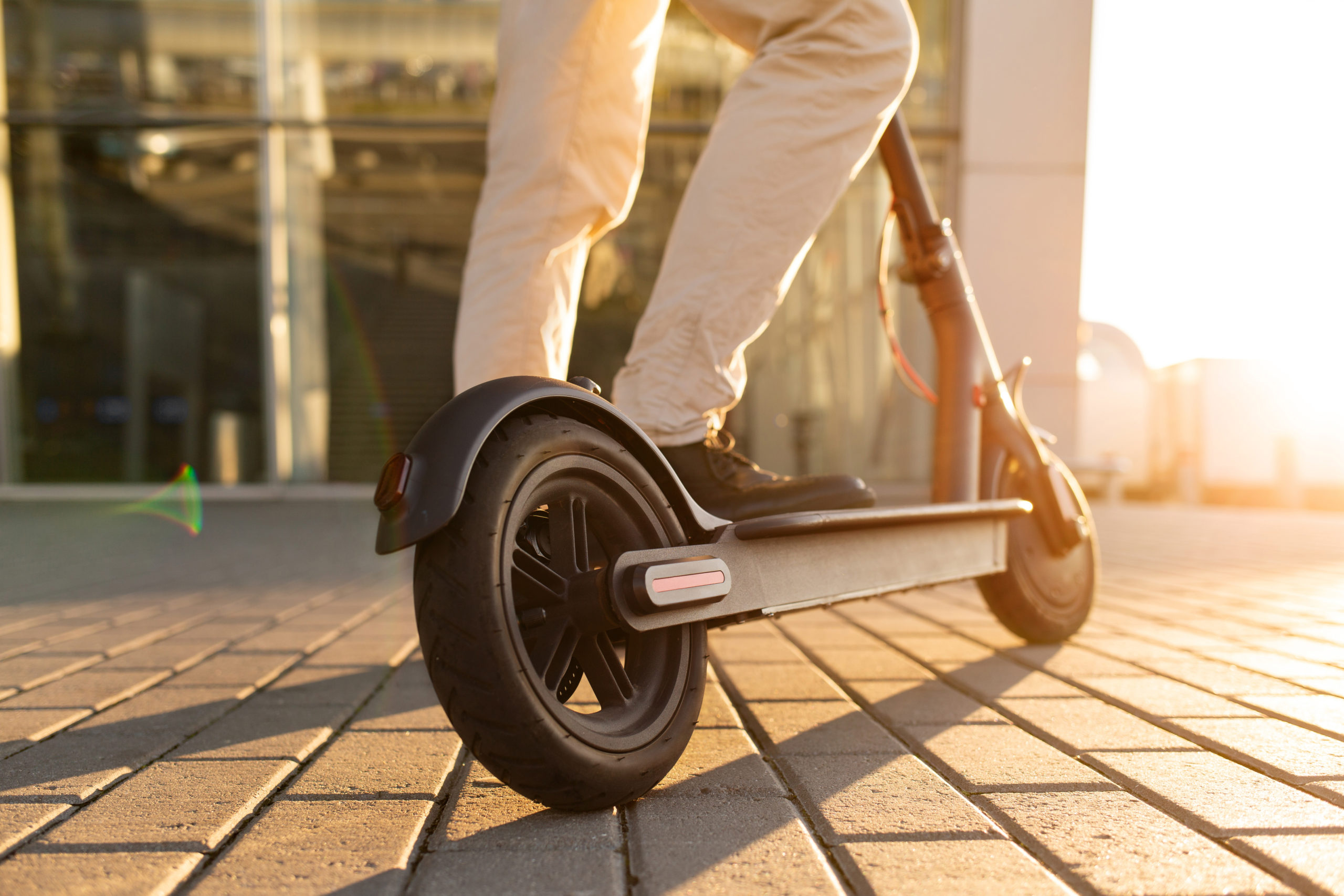 a man standing with one foot on an e-scooter